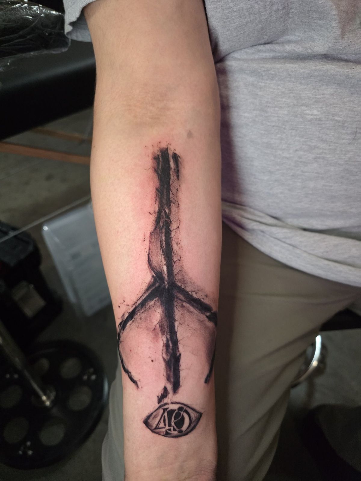 Black-and-red inverted cross and sword tattoo extending along the forearm