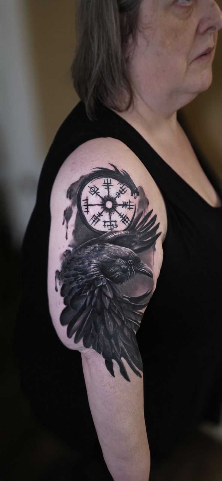 Black-and-gray raven and Vegvisir symbol tattoo on the shoulder