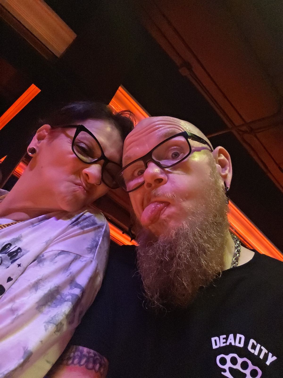 Tank and Sandra making playful faces in warm red light