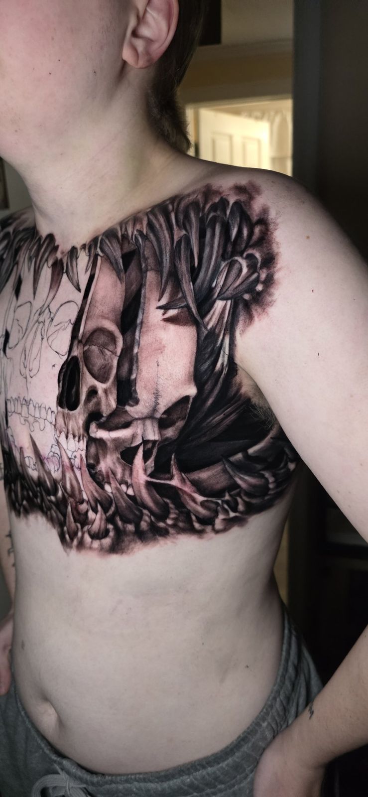 Detailed shaded skull and fang tattoo extending across the shoulder