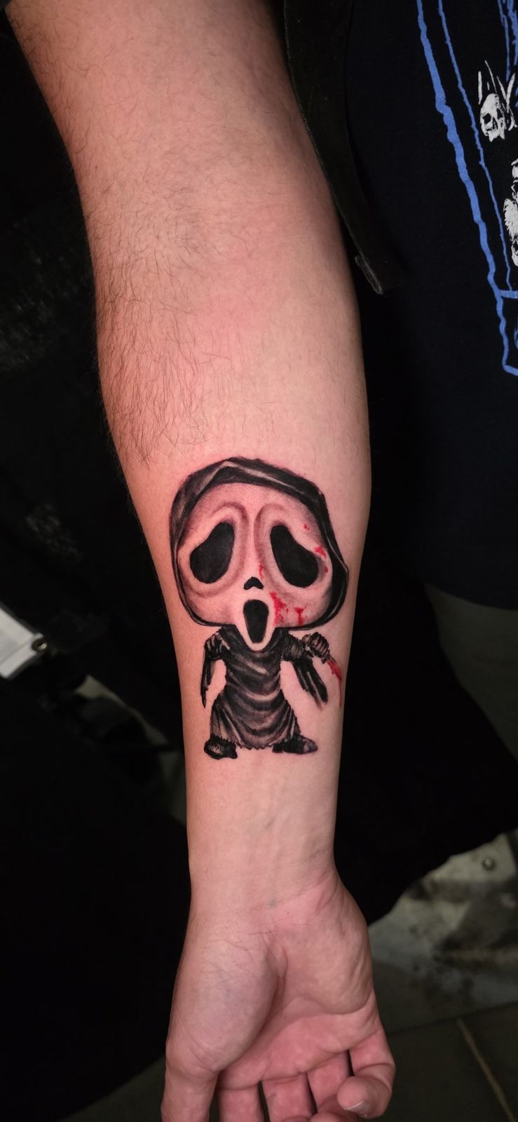 Small stylized hooded horror character tattoo with selective red accents