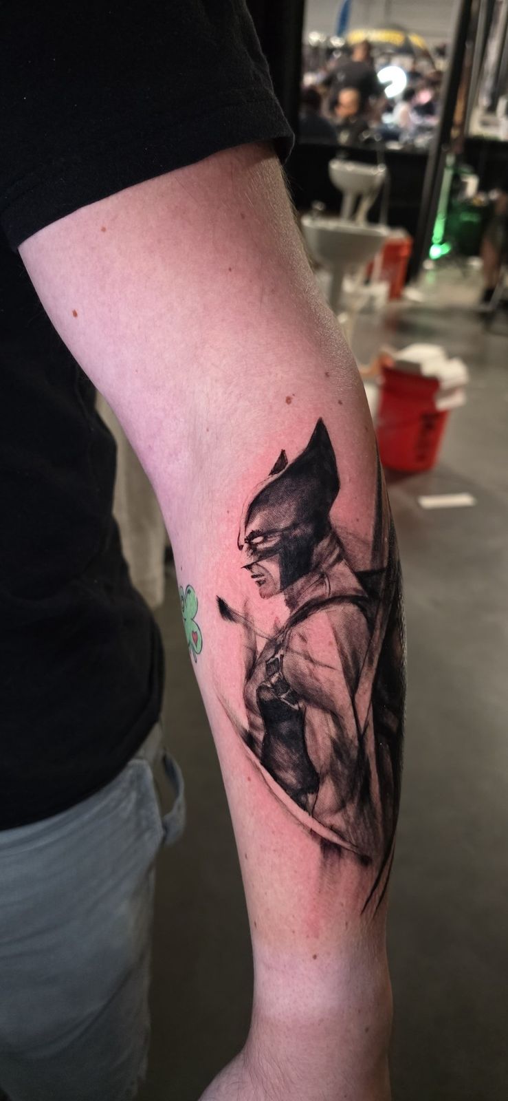 Side view of a black-and-gray Wolverine portrait tattoo on the forearm