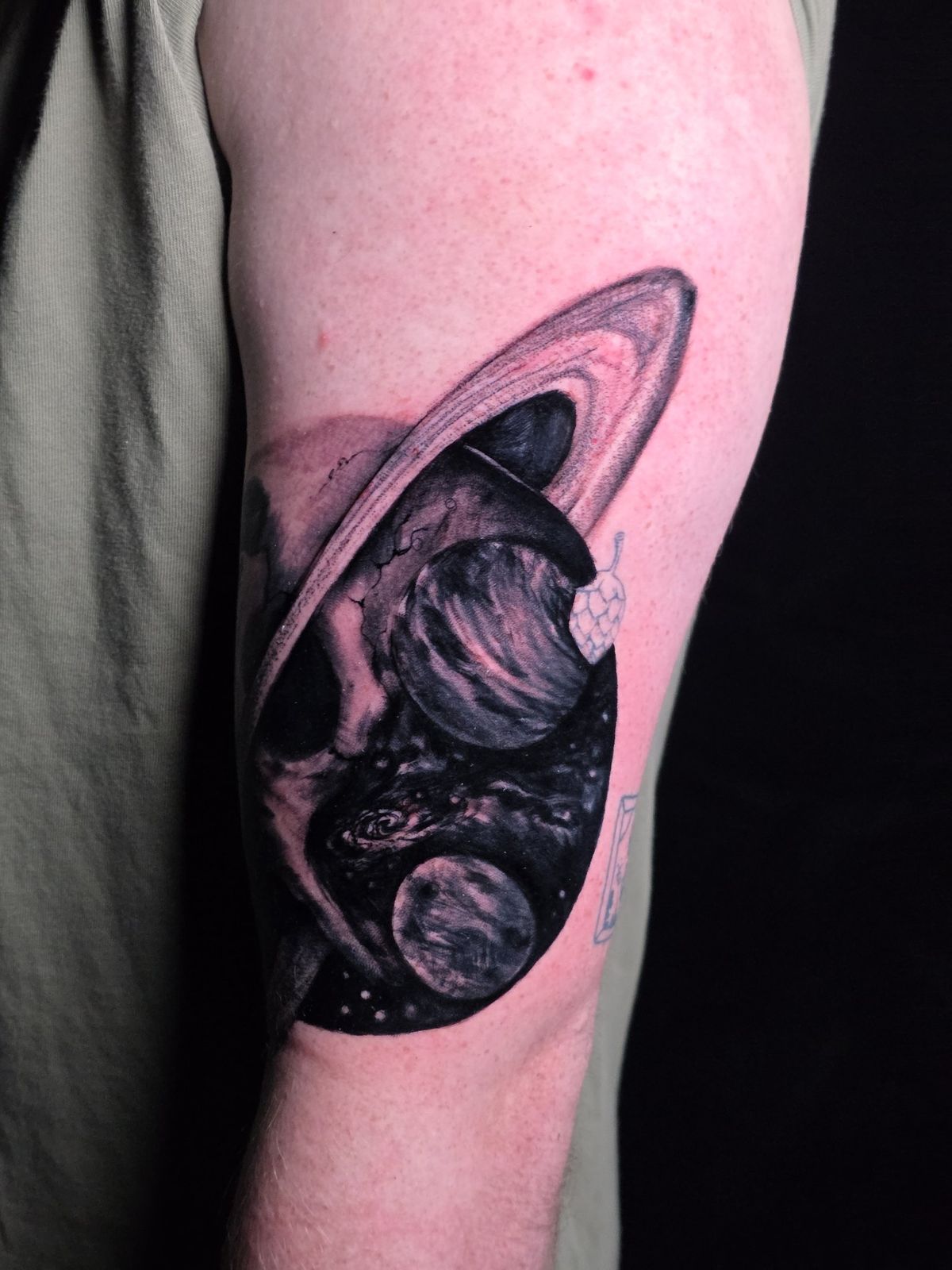 Close view of a skull and Saturn-inspired black-and-gray forearm tattoo