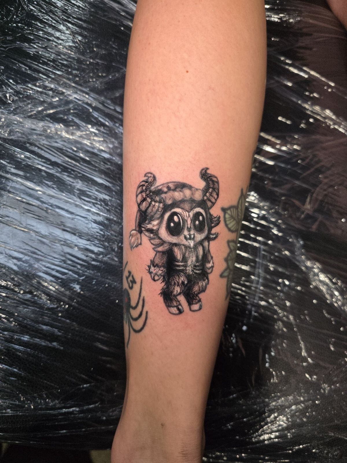 Chibi-style horned demon character tattoo on the forearm