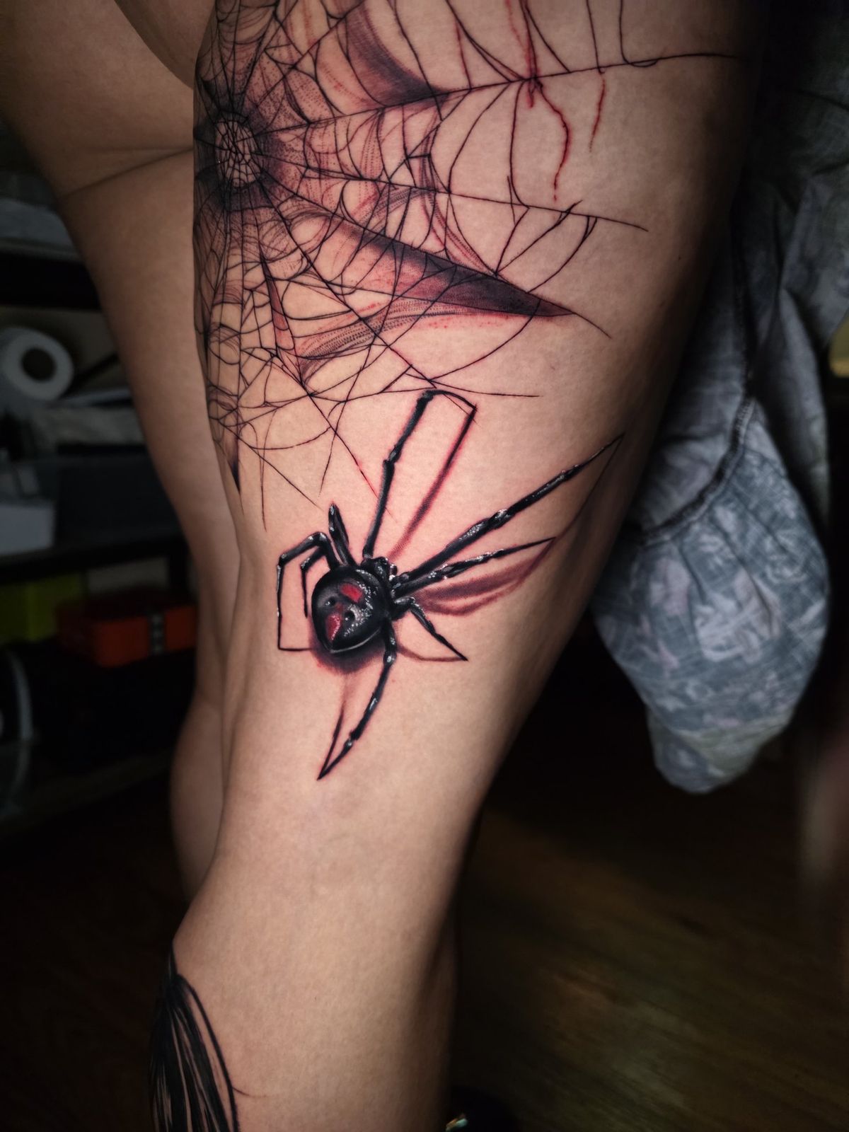 Black widow spider and web tattoo wrapping the knee