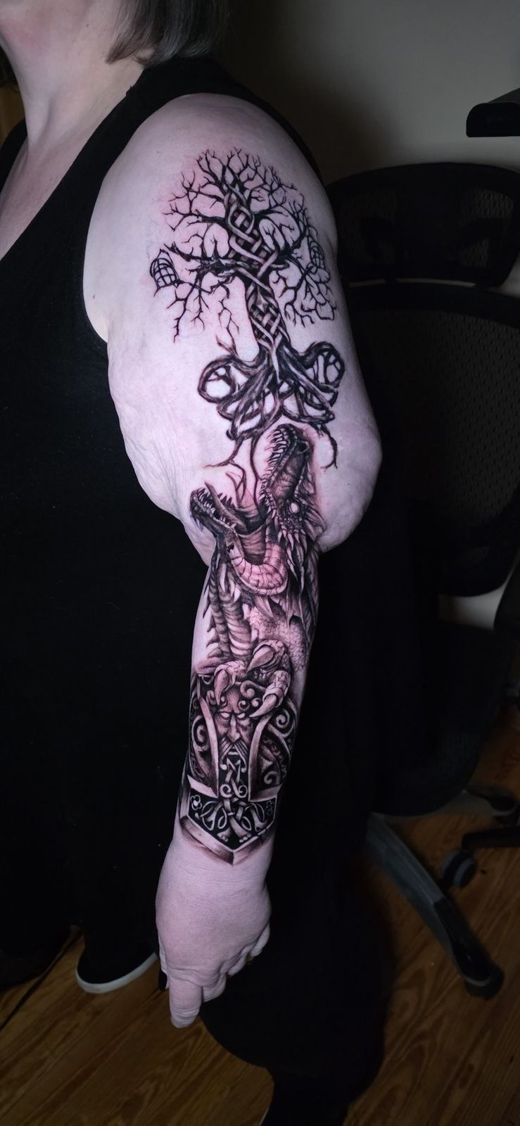 Black-and-gray dragon, tree and hammer sleeve shown from shoulder to wrist