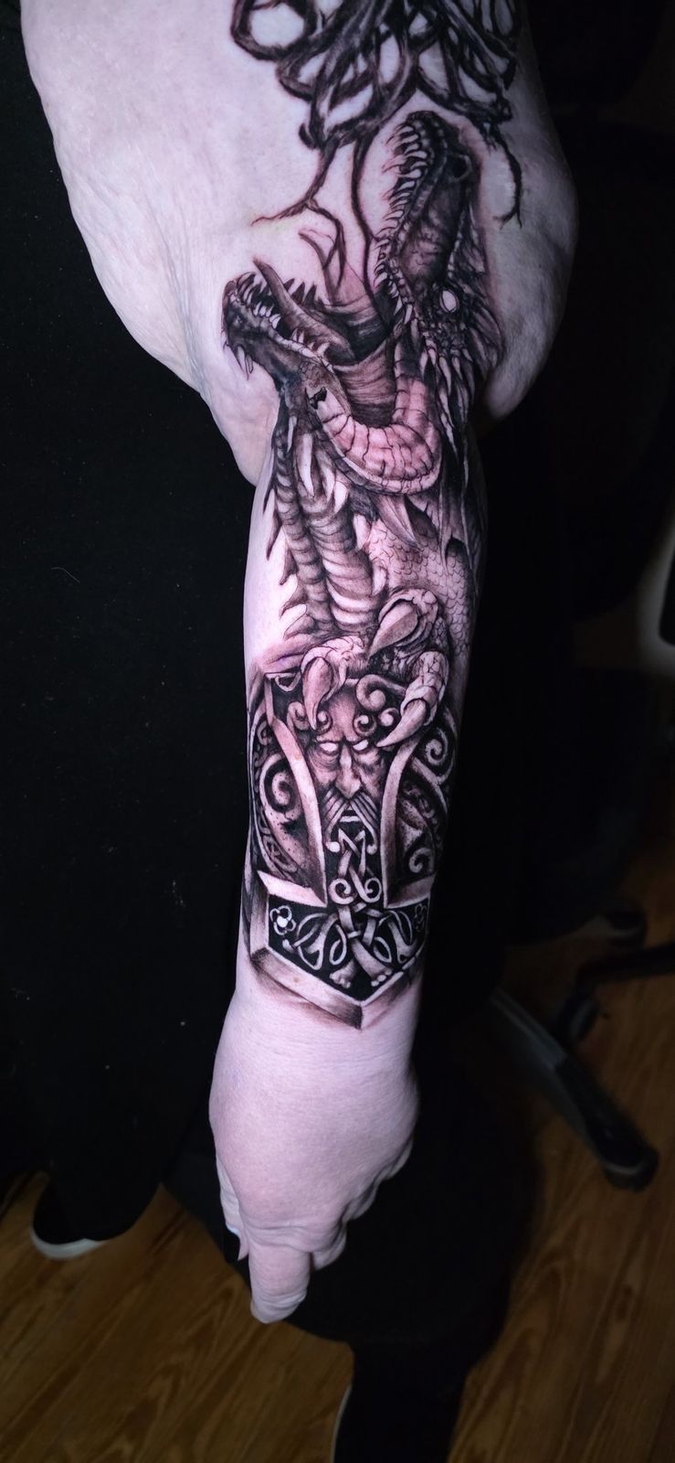 Close view of a detailed black-and-gray dragon wrapped around an ornate hammer