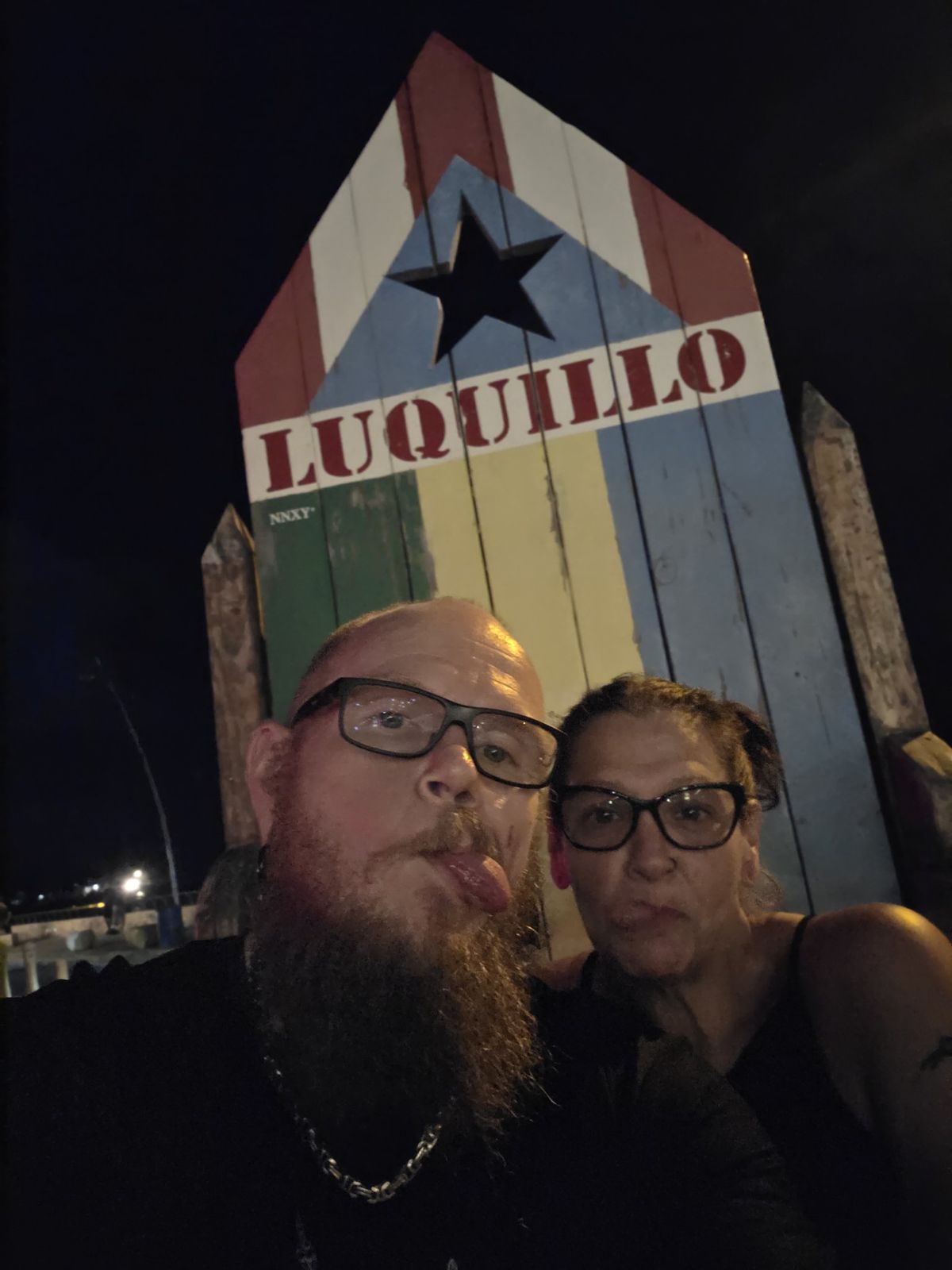 Tank and Sandra taking a nighttime selfie beneath the Luquillo sign