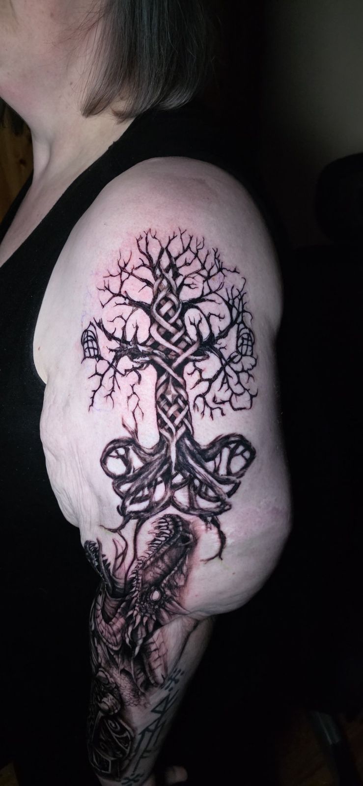 Upper-arm detail of a gnarled tree above a black-and-gray dragon