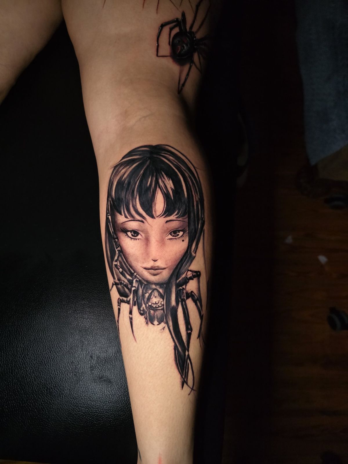 Black spider and anime-inspired girl portrait tattoo on the forearm
