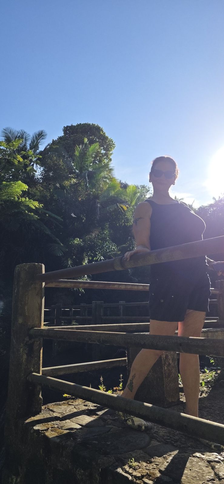 Sandra standing on a bridge in bright tropical sunlight
