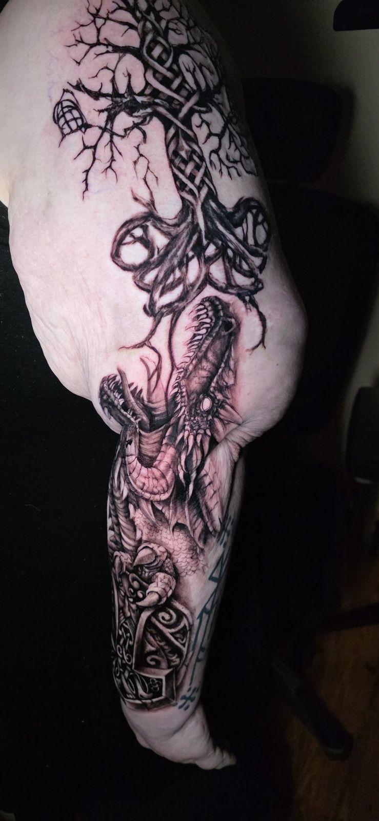 Side view of a black-and-gray dragon and tree sleeve