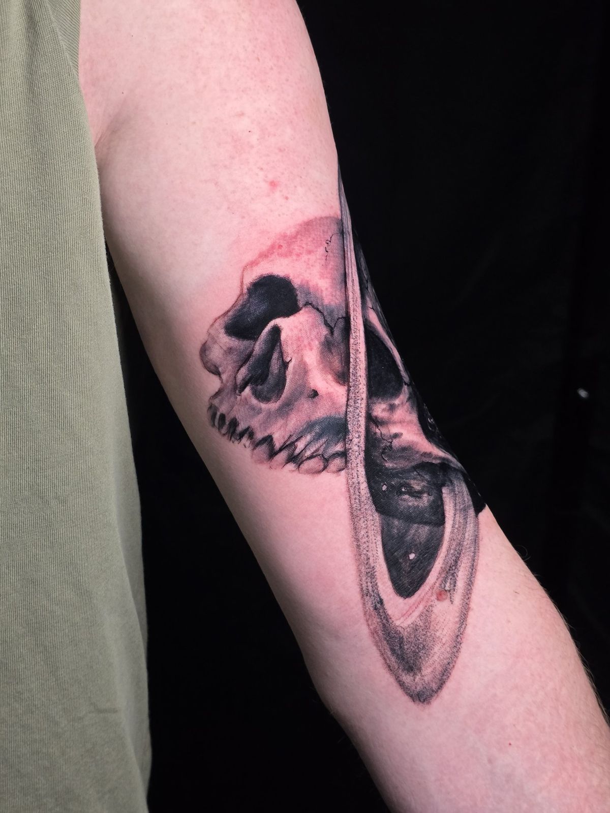 Black-and-gray skull and ringed planet composition on the forearm